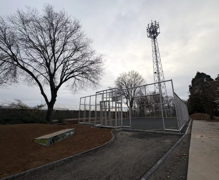 „Baustelle betreten verboten!“ heißt es derzeit noch für die Skateanlage am Freizeitgelände Süd. Hinter dem verschlossenen Tor steht bereits der fertiggestellte Edelstahl-Cage, dessen Konstruktion mit den eingespannten Stahlseilelementen gut zu erkennen ist. Diese besondere Bauweise bildet den sogenannten „Silent Cage“, der Ballspielgeräusche deutlich reduziert. Die Anlage fügt sich bereits gut in das Freizeitgelände ein. Foto: Stadt Griesheim